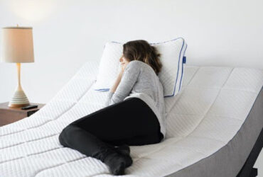 A woman resting on a memory foam mattress with a side sleeper design in a modern bedroom.