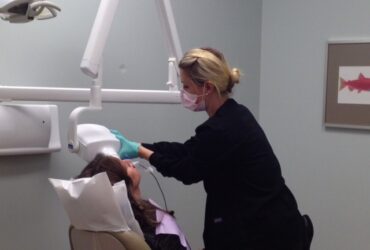 Dental hygienist performing oral examination on patient in dental clinic, health care, dentistry, patient care, teeth cleaning, medical professionalism.