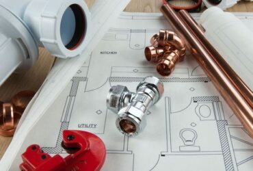 Modern plumbing components laid out on a house blueprint for construction or renovation.