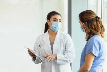 Wearing medical masks and discussing patient care in a healthcare facility.